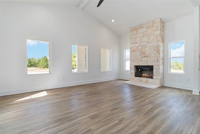 unfurnished living room with beam ceiling, hardwood / wood-style flooring, high vaulted ceiling, and plenty of natural light