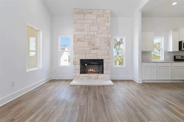 unfurnished living room featuring a wealth of natural light, light wood-type flooring, and a fireplace