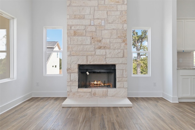 unfurnished living room with a healthy amount of sunlight, light wood-type flooring, and a stone fireplace