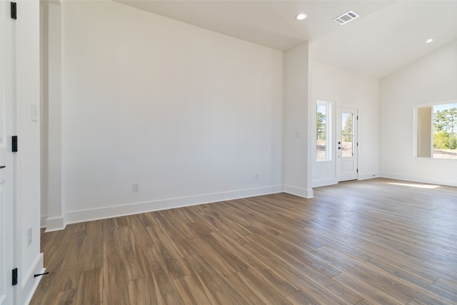 spare room with a wealth of natural light, vaulted ceiling, and dark hardwood / wood-style flooring