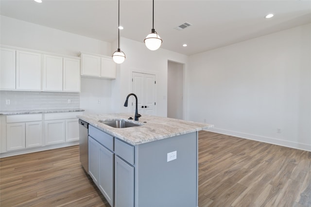 kitchen with pendant lighting, sink, white cabinets, and a kitchen island with sink