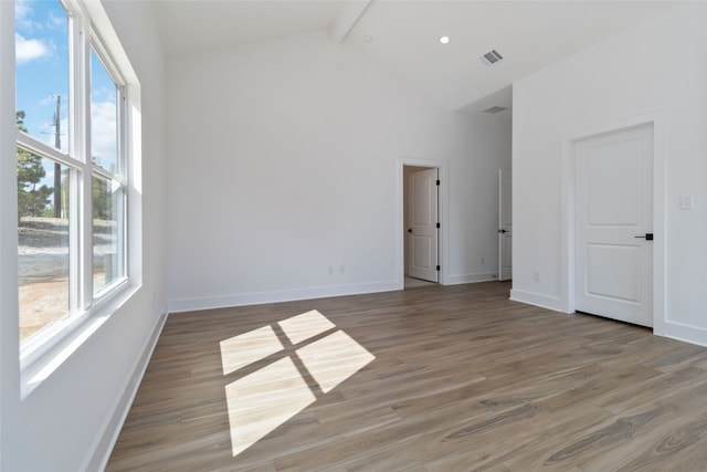 empty room with hardwood / wood-style flooring, a healthy amount of sunlight, beamed ceiling, and high vaulted ceiling