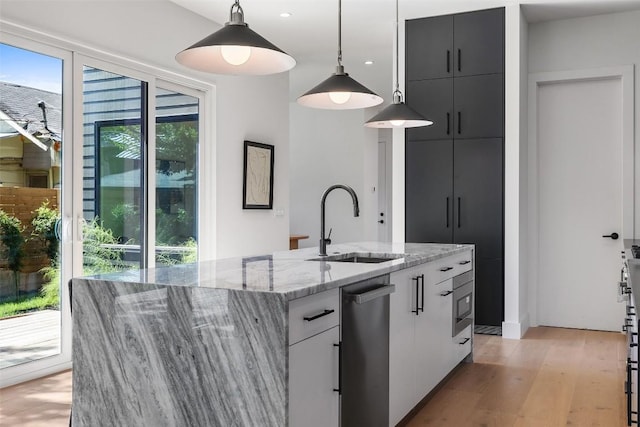 kitchen featuring sink, white cabinetry, an island with sink, and hanging light fixtures