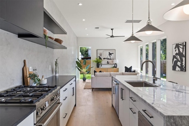 kitchen with sink, an island with sink, appliances with stainless steel finishes, decorative light fixtures, and white cabinetry