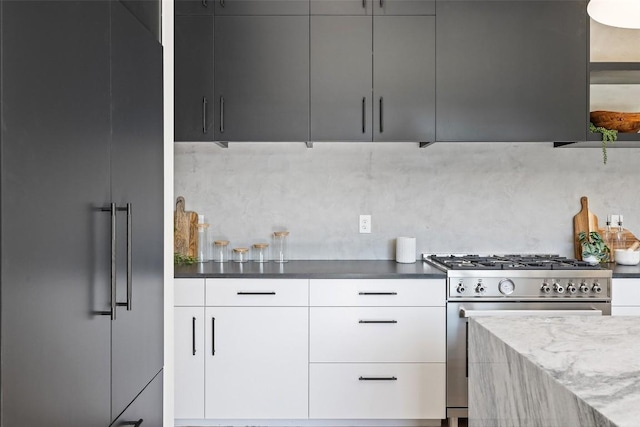 kitchen with backsplash, dark stone countertops, high quality appliances, and white cabinetry