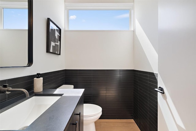 bathroom with vanity, toilet, tile walls, and a wealth of natural light