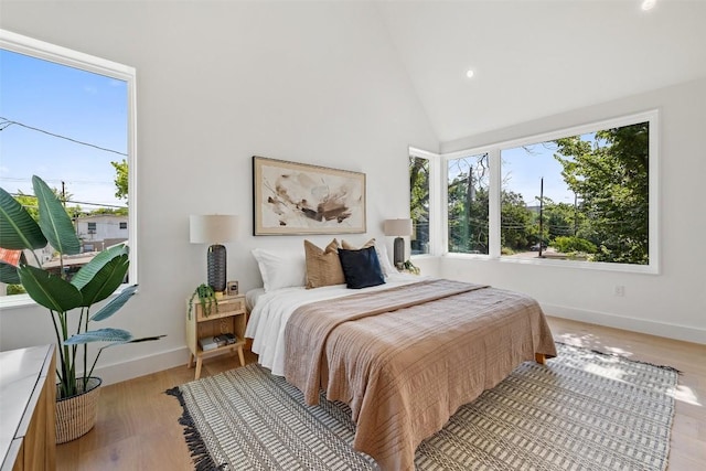 bedroom featuring high vaulted ceiling and light hardwood / wood-style floors