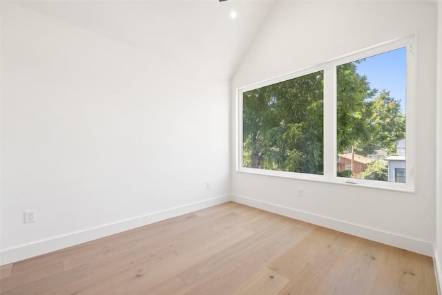 spare room with lofted ceiling and light wood-type flooring