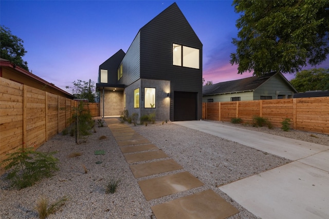 back house at dusk featuring a garage