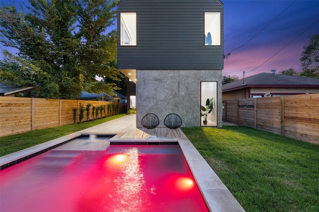 pool at dusk featuring a lawn