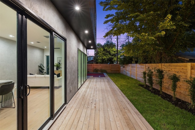 deck at dusk featuring a lawn