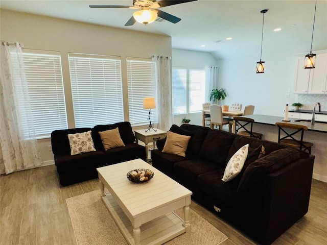 living room featuring sink, light wood-type flooring, and ceiling fan