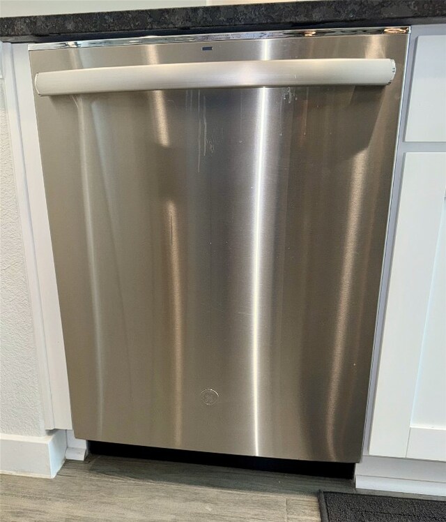 interior details with dishwasher, white cabinetry, and light wood-type flooring