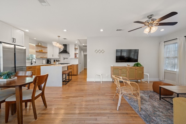 living room featuring light wood-type flooring, ceiling fan, and sink