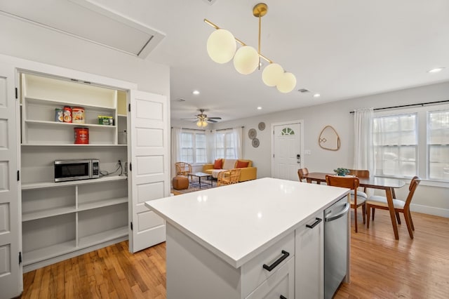 kitchen featuring ceiling fan, white cabinetry, stainless steel appliances, hanging light fixtures, and a kitchen island