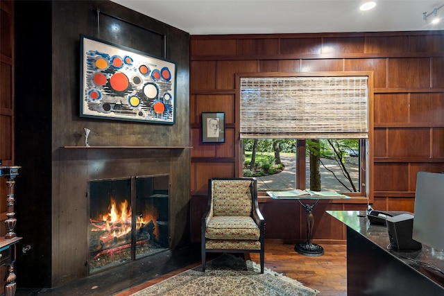 sitting room with wooden walls and wood-type flooring