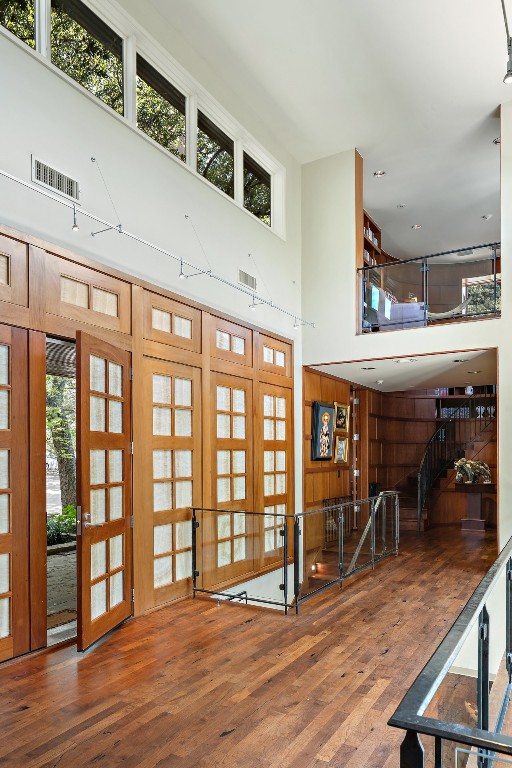 entrance foyer with a towering ceiling, hardwood / wood-style floors, a healthy amount of sunlight, and french doors