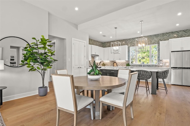 dining space featuring light wood-type flooring and a notable chandelier