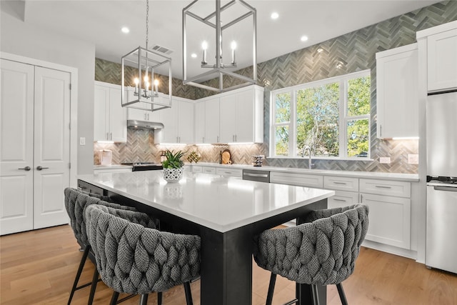 kitchen with white cabinets, pendant lighting, a center island, and a kitchen bar