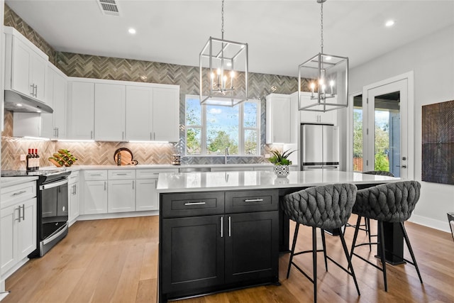 kitchen with a kitchen island, white cabinets, appliances with stainless steel finishes, and pendant lighting