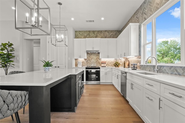 kitchen featuring white cabinets, stainless steel appliances, pendant lighting, a kitchen island, and sink