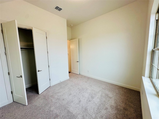 unfurnished bedroom featuring light carpet and a closet