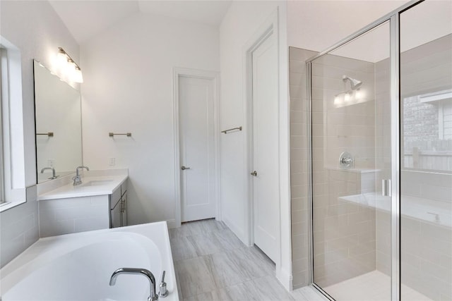 bathroom featuring lofted ceiling, a stall shower, a garden tub, and vanity