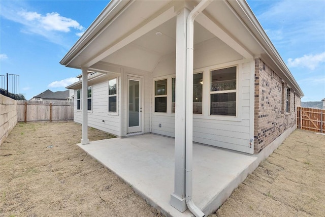 rear view of property featuring a patio, brick siding, and a fenced backyard