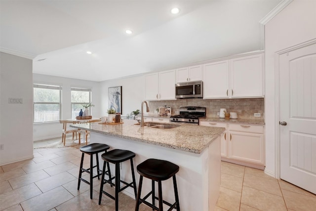 kitchen with appliances with stainless steel finishes, white cabinets, a kitchen island with sink, and sink