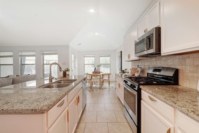 kitchen with a kitchen island with sink, crown molding, sink, appliances with stainless steel finishes, and light stone counters