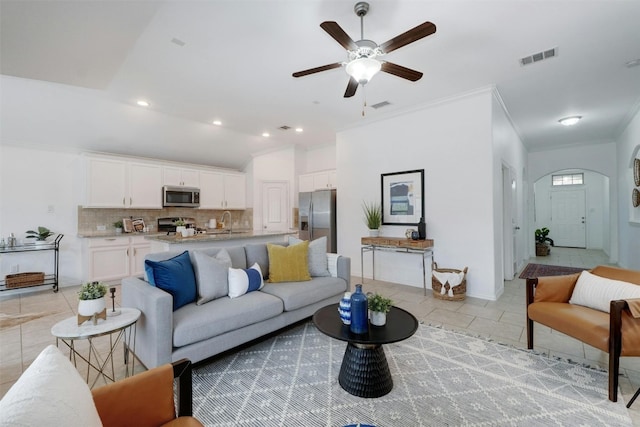 tiled living room with ceiling fan, crown molding, and sink