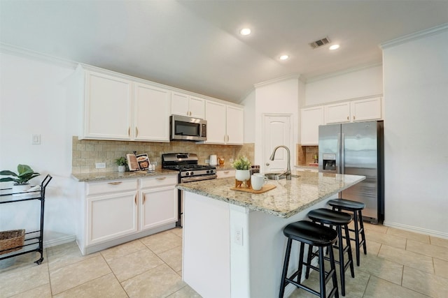 kitchen featuring white cabinetry, stainless steel appliances, and an island with sink