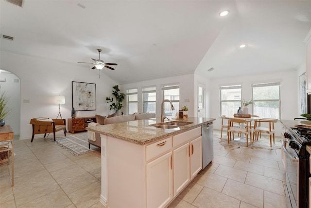 kitchen with sink, a center island with sink, light stone counters, and a wealth of natural light