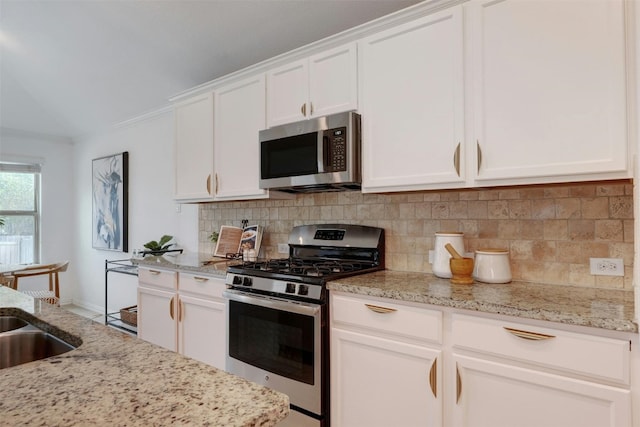 kitchen with light stone counters, stainless steel appliances, tasteful backsplash, and white cabinets