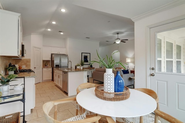 tiled dining area with crown molding, sink, and ceiling fan