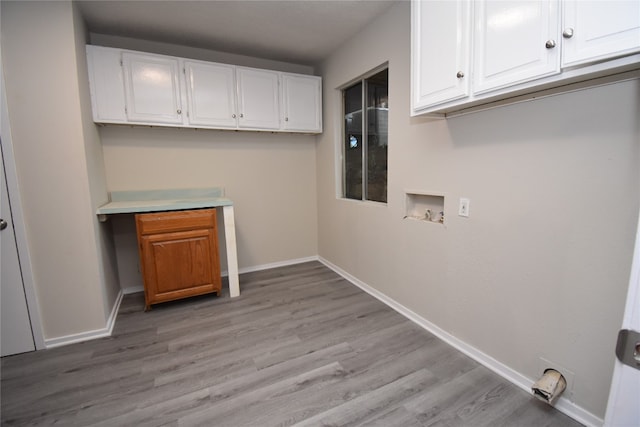 clothes washing area with washer hookup, light hardwood / wood-style floors, and cabinets