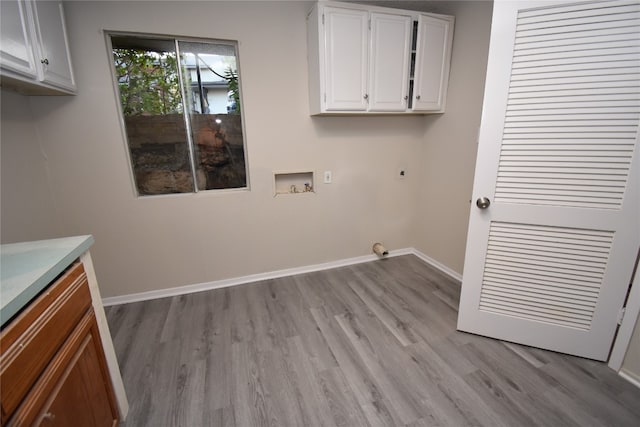 clothes washing area featuring hookup for an electric dryer, light hardwood / wood-style flooring, hookup for a washing machine, and cabinets