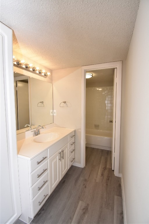 bathroom with vanity, a textured ceiling, tiled shower / bath combo, and wood-type flooring