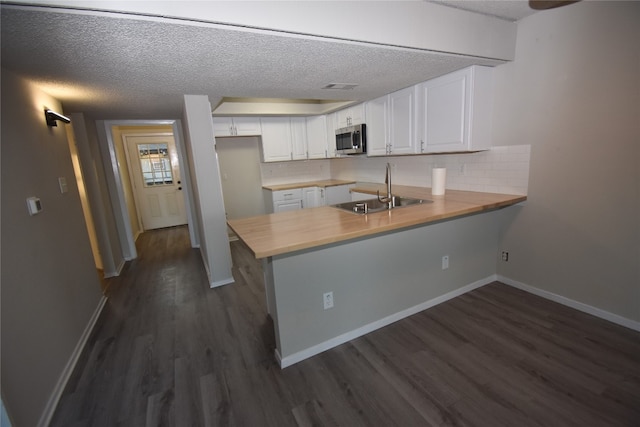 kitchen featuring kitchen peninsula, white cabinetry, sink, and dark hardwood / wood-style floors