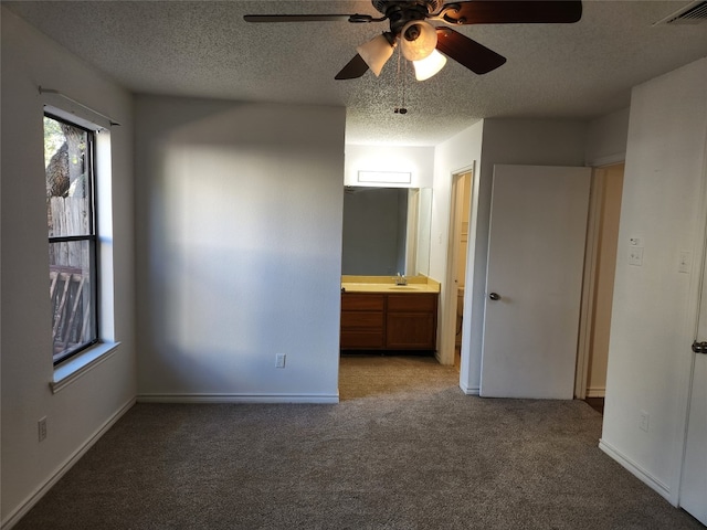 unfurnished bedroom featuring connected bathroom, ceiling fan, a textured ceiling, and light colored carpet