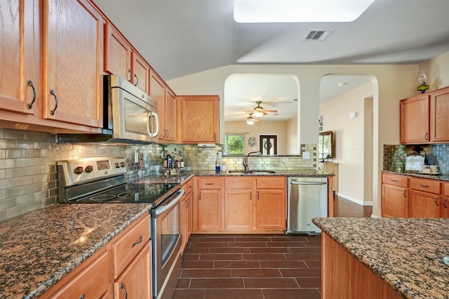 kitchen with sink, stainless steel appliances, backsplash, and dark stone counters