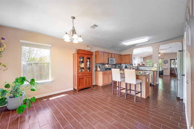 kitchen featuring appliances with stainless steel finishes, a breakfast bar, tasteful backsplash, and dark hardwood / wood-style flooring