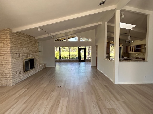 unfurnished living room with light hardwood / wood-style floors, lofted ceiling with skylight, and a fireplace