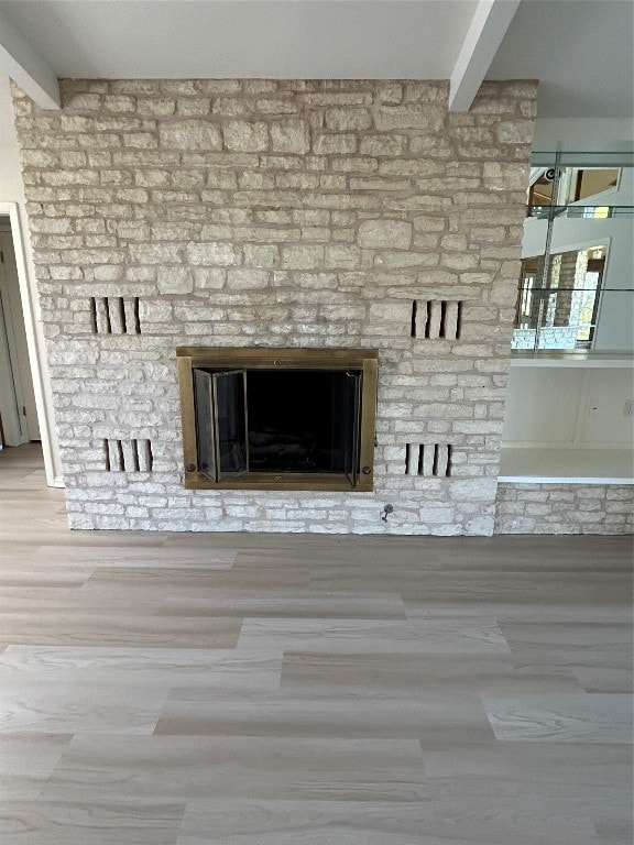 details with beam ceiling, hardwood / wood-style flooring, and a large fireplace