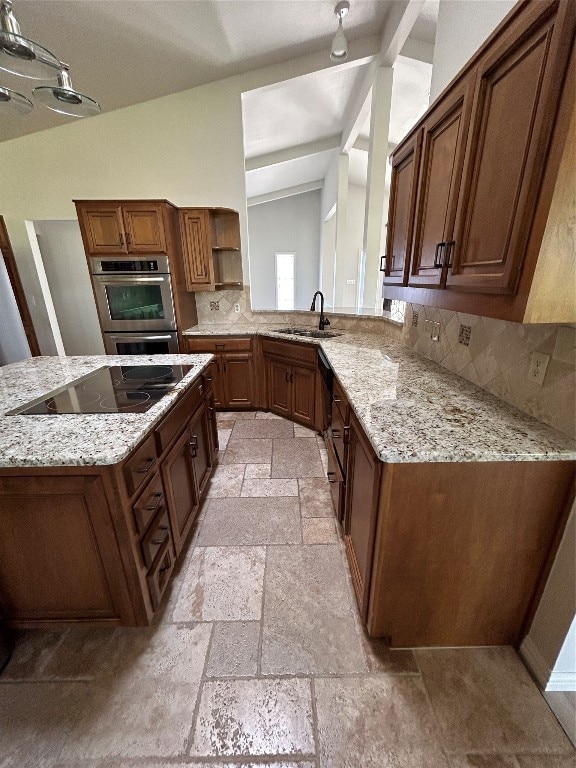 kitchen with black electric stovetop, light stone counters, lofted ceiling, and sink