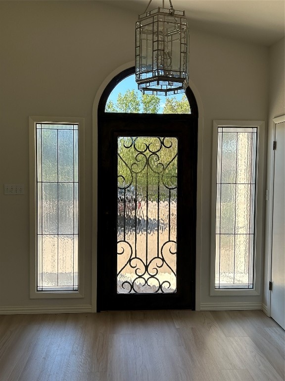 entrance foyer with an inviting chandelier, plenty of natural light, and hardwood / wood-style floors