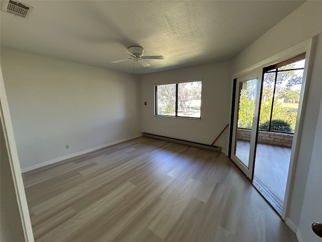 unfurnished room with a baseboard heating unit, a textured ceiling, light hardwood / wood-style floors, and ceiling fan