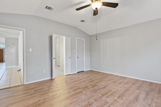 unfurnished bedroom featuring lofted ceiling, light hardwood / wood-style flooring, a textured ceiling, and ceiling fan