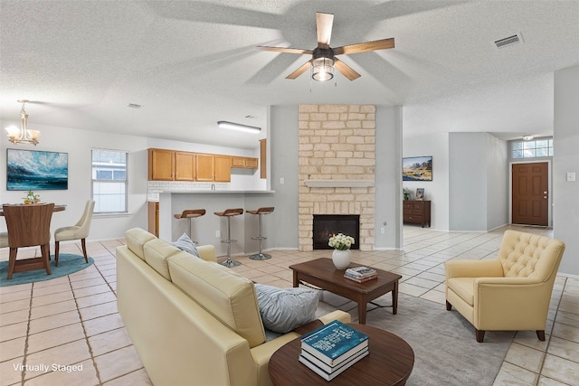 tiled living room featuring a healthy amount of sunlight, a textured ceiling, and a stone fireplace