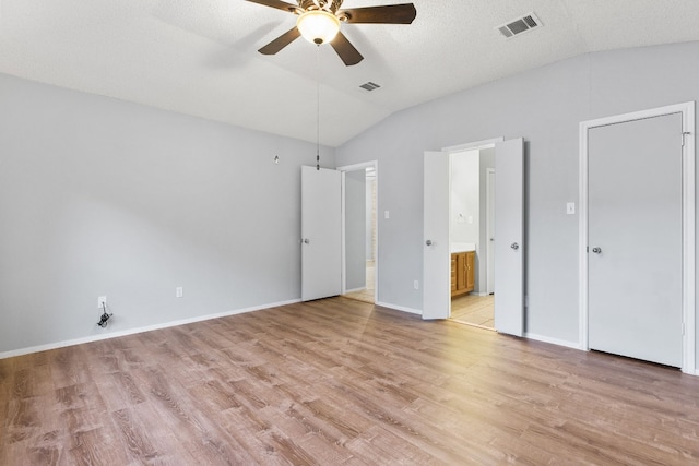 unfurnished bedroom with ensuite bathroom, a textured ceiling, ceiling fan, light hardwood / wood-style floors, and vaulted ceiling